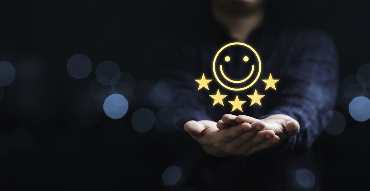 Hands holding a superimposed 5-star symbol and happy face indicating customer satisfaction.